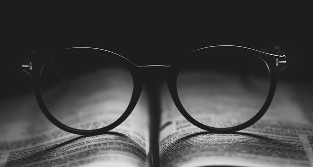 Photographie de lunettes posées sur un livre ouvert